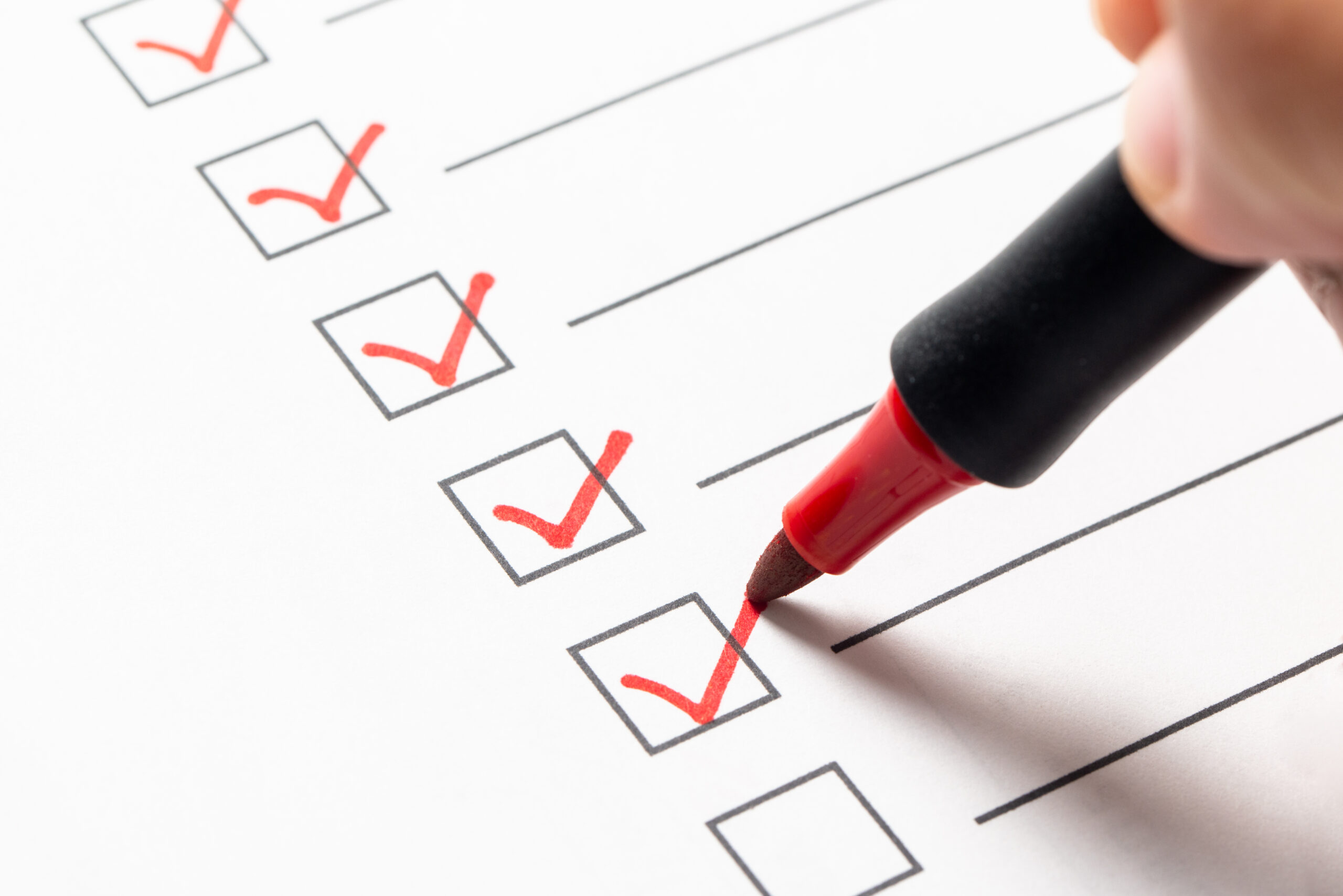 Checklist box with a hand using a red marker pen to check off items